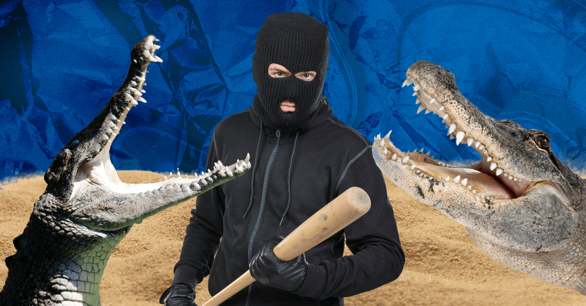 A masked man wearing all black holds a baseball bat surrounded by two open-mouthed crocodiles.