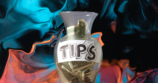 A tip jar full of cash against a blue and peach background. 